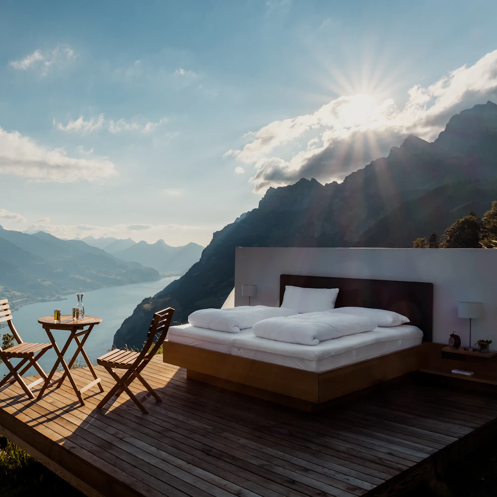 Open-air bed on a timber deck above a mountain lake